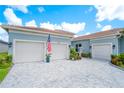 A view of the two-car garage with a paved driveway and landscaped yard at 4926 Pamplona Ct, Wimauma, FL 33598