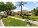A beautifully landscaped home with a lush green lawn, mature trees, and a well-maintained exterior at 5123 Whispering Leaf Trl, Valrico, FL 33596