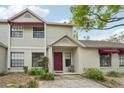Charming townhome with a red front door, awning, and well-maintained landscaping at 8419 Laurelon Pl, Temple Terrace, FL 33637
