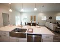 Bright, open-concept kitchen featuring a stainless steel farmhouse sink and sleek white countertops at 9445 Eldridge Rd, Spring Hill, FL 34608