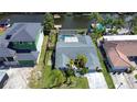 Aerial view of a home with a screened-in pool, a dock, and water access, surrounded by lush landscaping at 9826 Island Harbor Dr, Port Richey, FL 34668