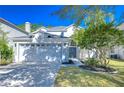 Charming home featuring a two-car garage, well-manicured lawn, and classic architectural details under a clear blue sky at 10538 Lucaya Dr, Tampa, FL 33647