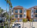 Three-story exterior featuring two-car garages, balconies, tile roof, and manicured landscaping with beautiful palm trees at 17821 Gulf Blvd # B, Redington Shores, FL 33708