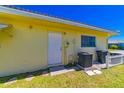 The back of the home has a white door, AC unit, and trash cans near a green lawn at 5427 Springwood Blvd # 5427, Pinellas Park, FL 33782