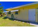 Rear exterior features a white door, awning-covered windows, and a neatly kept lawn at 5427 Springwood Blvd # 5427, Pinellas Park, FL 33782