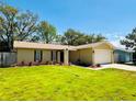 Well-kept single-story home with a lush green lawn and mature trees surrounding the property at 10320 White Cedar St, Port Richey, FL 34668