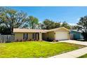 Well-kept single-story home with a lush green lawn and mature trees surrounding the property at 10320 White Cedar St, Port Richey, FL 34668