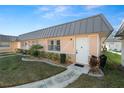 Welcoming single-story home with a metal roof, neat landscaping, and a pathway to the front door at 11719 Boynton Lane, New Port Richey, FL 34654
