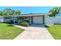Charming single-story home featuring a well-manicured lawn and a private driveway leading to an attached garage at 13596 Croft N Dr, Largo, FL 33774