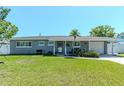 Charming single-story home with well-maintained lawn and a welcoming front entrance and freshly painted gray exterior at 13596 Croft N Dr, Largo, FL 33774