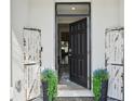 Inviting entryway featuring a stylish black door, decorative planters, and charming farmhouse decor at 16646 Maude Dr, Wimauma, FL 33598