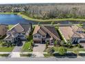 Aerial view of a home with a tile roof, screened in patio, a lake and lush landscaping at 4681 Night Star Trl, Odessa, FL 33556
