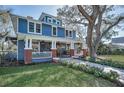 Charming two-story blue home with a welcoming front porch and beautifully landscaped front yard at 527 Scotland St, Dunedin, FL 34698