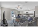 Spacious living room with gray sofa, an open layout, and sliding door to backyard at 7229 Spring Snowflake Ave, Tampa, FL 33619
