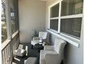 Cozy screened porch with seating featuring plush chairs, foot stools, and a small round table at 10126 Bahama Ct, Seminole, FL 33776