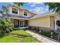 Charming two-story home featuring yellow siding, a screened-in porch, and landscaped front yard at 2199 Springrain Dr, Clearwater, FL 33763