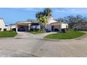 Charming home featuring a spacious driveway, carport, and lush landscaping with mature palm trees at 2572 Forest Run Ct, Clearwater, FL 33761