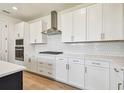 A bright kitchen featuring white cabinets, an island, and stainless steel vent over the cooktop at 2832 Marrakesh Ln, Sarasota, FL 34234