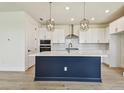 Modern kitchen features white cabinets, stylish light fixtures, stainless steel appliances, and a large island at 2832 Marrakesh Ln, Sarasota, FL 34234