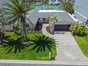 Aerial view of home with lush landscaping, brick driveway, and mature palm trees at 556 Johns Pass Ave, Madeira Beach, FL 33708
