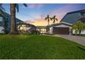 Beautiful home with brick driveway, lush landscaping, and mature palm trees at sunset at 556 Johns Pass Ave, Madeira Beach, FL 33708