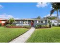 Charming single-story home featuring a well-maintained lawn, inviting front porch, and vibrant landscaping with a brick walkway at 6727 Burlington N Ave, St Petersburg, FL 33710