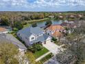 Aerial view of a home near a tranquil lake surrounded by lush greenery and other residences at 10220 Deercliff Dr, Tampa, FL 33647