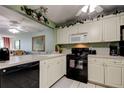 Charming kitchen with white cabinetry, black appliances, and an adjacent dining area at 14130 Rosemary Ln # 1201, Largo, FL 33774