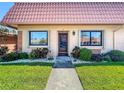 Charming condo exterior featuring a well-manicured lawn, lush shrubs, white rock beds, and a covered entryway at 19029 Us Highway 19 N # 27A, Clearwater, FL 33764