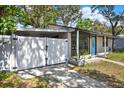 Street view of charming single-story home featuring a bright blue front door and a private fenced-in carport at 1908 E Mcberry St, Tampa, FL 33610