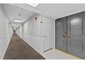 Well-lit hallway leads to a double door entry featuring neutral paint and carpet at 220 Belleview Blvd # 701, Belleair, FL 33756