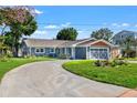 Charming blue home features a curved driveway, manicured lawn, and beautiful landscaping for great curb appeal at 292 Sunlit Cove Ne Dr, St Petersburg, FL 33702