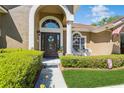 Inviting front entryway with a decorative door, arched window, and manicured landscaping at 3627 Cypress Meadows Rd, Tampa, FL 33624