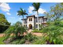 Beautiful exterior shot of a Mediterranean home highlighting the palm trees, arched entry, and red brick driveway at 44 Martinique Ave, Tampa, FL 33606