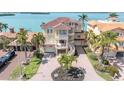 Stunning waterfront home with a red tile roof, spiral staircase, and circular driveway surrounded by palm trees at 700 126Th Ave, Treasure Island, FL 33706