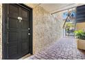 A covered entrance with a black front door, stone pavers, and textured stucco wall offers an inviting welcome at 107 S Obrien St # 117, Tampa, FL 33609