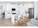 Bright kitchen with white cabinets, stainless steel appliances, an island with bar stools and modern light fixtures at 11795 Starbright Path, Venice, FL 34293