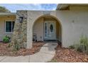 Close-up of the arched front entryway, showcasing stone details and a decorative glass front door with house number at 12299 91St N Ave, Seminole, FL 33772