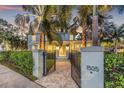 Inviting two-story home featuring a beautifully landscaped entrance and a wrought iron gate with brick pathway at 1505 Beach Ne Dr, St Petersburg, FL 33704