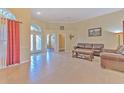 Spacious living room featuring tile floors, a leather sofa set, and a large window with red curtains at 3217 Partridge Point Trl, Valrico, FL 33596
