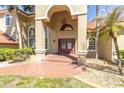 Elegant home entrance featuring arched windows, an ornate light fixture, and a brick-paved walkway at 4404 Lake In The Woods Dr, Spring Hill, FL 34607