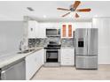 Bright kitchen features white cabinets, stainless steel appliances, and tile backsplash at 100 Bluff View Dr # 409C, Belleair Bluffs, FL 33770