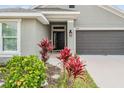 Close up of a home entrance with well kept landscaping, a black front door and gray two car garage door at 14916 Imperial Purple Ln, Wimauma, FL 33598