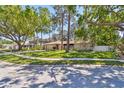 Desirable single-story home boasts a lush green lawn, mature shade trees, and stone facade at 3034 Gull Pl, Clearwater, FL 33762
