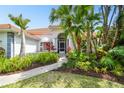 Beautifully landscaped front entrance with a screened porch and tropical foliage at 441 Village Dr, Tarpon Springs, FL 34689
