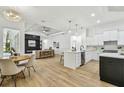 Bright open-concept living space with wood floors, a fireplace, modern lighting, and a view of the kitchen at 6314 Soratrace St, Lithia, FL 33547