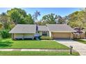 Charming single Gathering home features a well-maintained lawn, neutral paint, and rock accents at 864 Pinewood W Ter, Palm Harbor, FL 34683