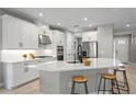 Modern kitchen with white cabinets, stainless steel appliances, and a large center island with stool seating at 2612 Leafwing Ct, Palm Harbor, FL 34683