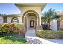 Inviting front entrance with an arched brick doorway, decorative glass door, and lush landscaping at 2749 Bent Leaf Dr, Valrico, FL 33594