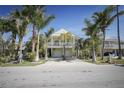 Charming coastal home featuring a light green exterior, white trim, and lush palm trees at 112 13Th Ave, Indian Rocks Beach, FL 33785